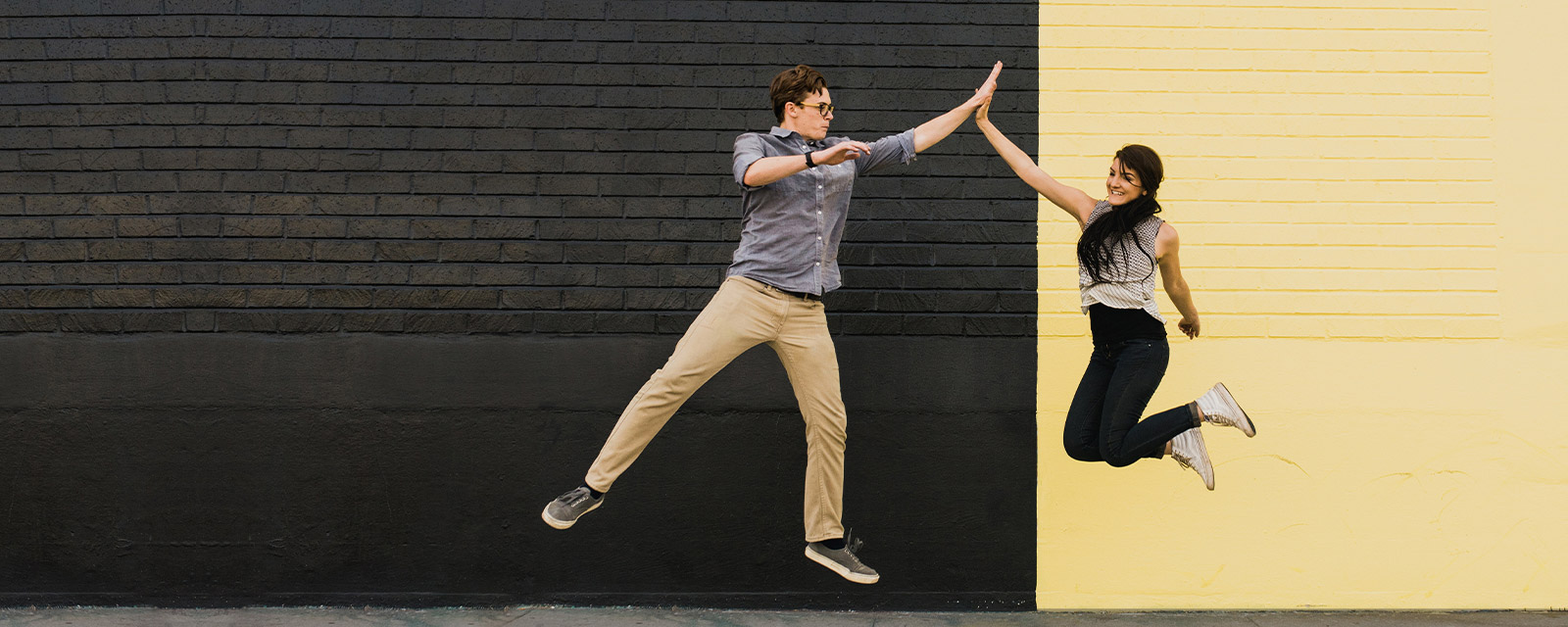 Two people jumping and high-fiving.